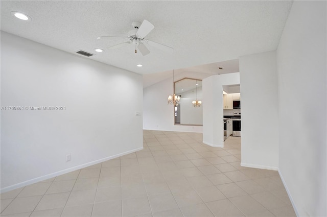 spare room with ceiling fan with notable chandelier, light tile patterned floors, and a textured ceiling