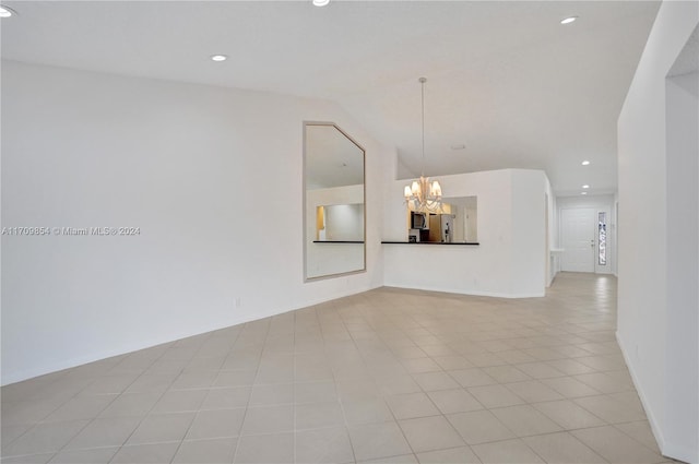 spare room featuring light tile patterned floors and a chandelier