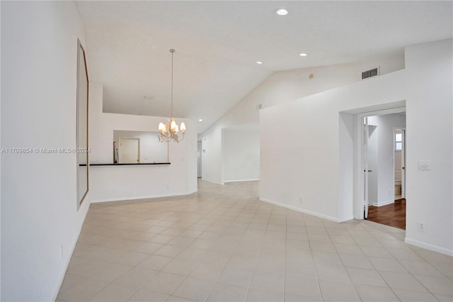 spare room with light tile patterned floors, high vaulted ceiling, and a notable chandelier