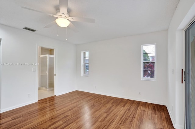 unfurnished bedroom featuring wood-type flooring, a textured ceiling, ensuite bathroom, and ceiling fan