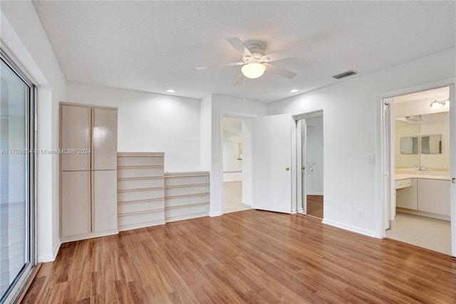 unfurnished bedroom with ensuite bath, ceiling fan, light hardwood / wood-style floors, a textured ceiling, and a closet