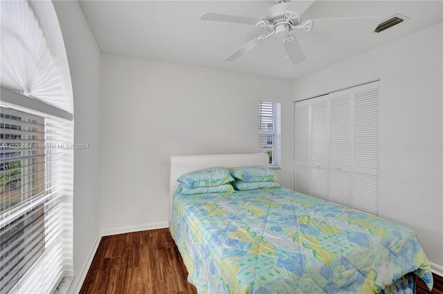 bedroom featuring dark hardwood / wood-style flooring, ceiling fan, and a closet