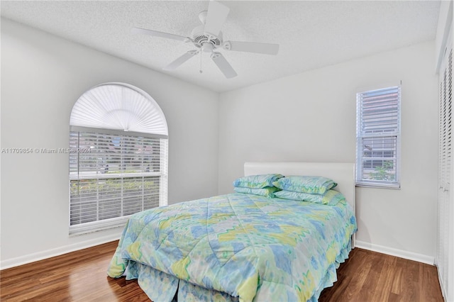 bedroom with multiple windows, ceiling fan, hardwood / wood-style floors, and a textured ceiling