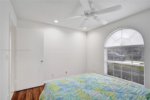 bedroom featuring a textured ceiling, dark hardwood / wood-style flooring, and ceiling fan