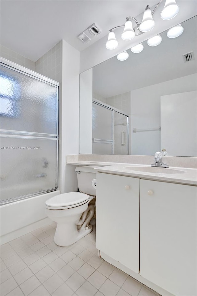 full bathroom with tile patterned floors, vanity, toilet, and bath / shower combo with glass door