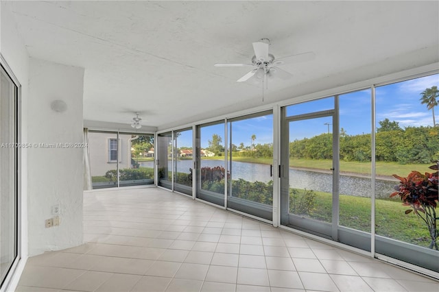 unfurnished sunroom featuring a water view, a wealth of natural light, and ceiling fan