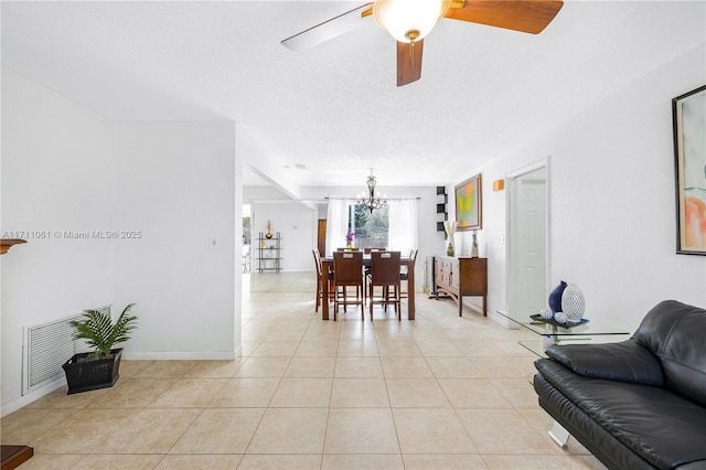 tiled living room with ceiling fan with notable chandelier and a textured ceiling