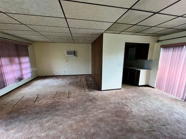 carpeted empty room featuring a paneled ceiling and a wall mounted AC