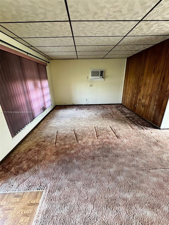 carpeted spare room featuring wooden walls and a wall unit AC