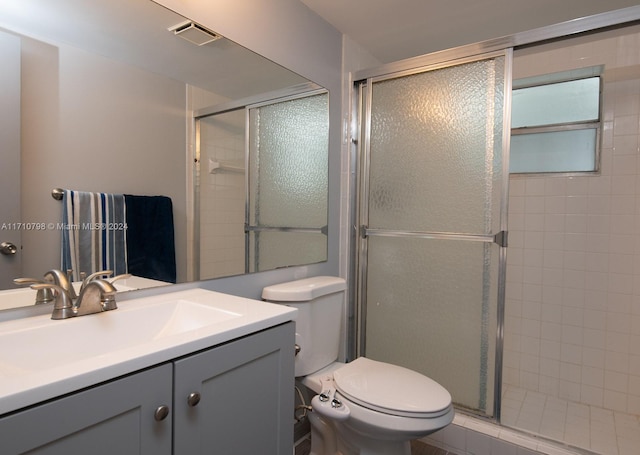 bathroom with vanity, a shower with shower door, and toilet