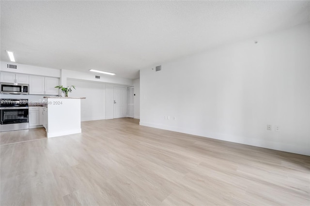 unfurnished living room with light hardwood / wood-style floors and a textured ceiling