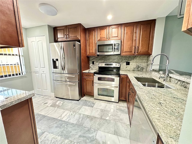 kitchen with stainless steel appliances, light stone countertops, sink, and decorative backsplash