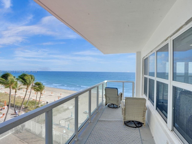 balcony featuring a view of the beach and a water view