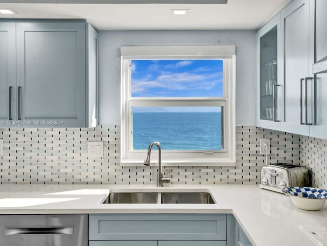 kitchen with dishwasher, a water view, sink, and tasteful backsplash