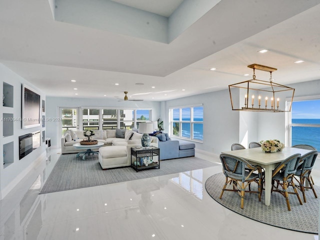 living room with a water view and ceiling fan with notable chandelier