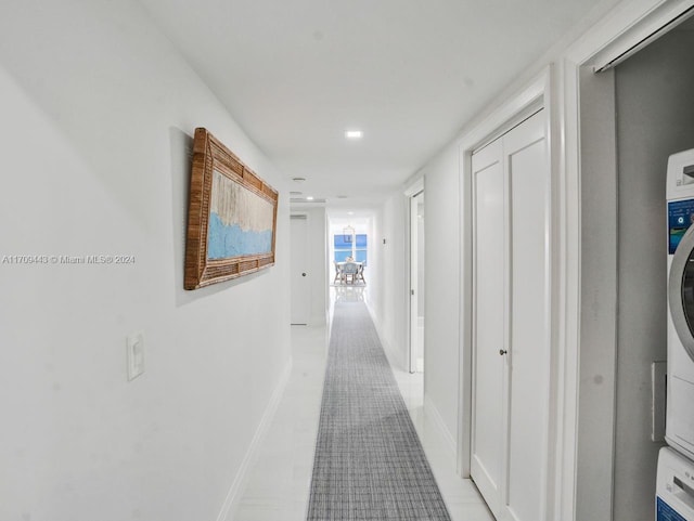 hall featuring light tile patterned floors and stacked washer and dryer