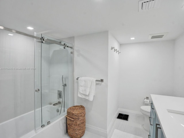 full bathroom with tile patterned floors, vanity, toilet, and bath / shower combo with glass door