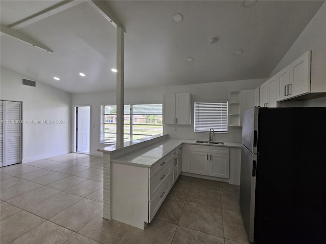 kitchen featuring white cabinetry, stainless steel fridge, sink, and vaulted ceiling