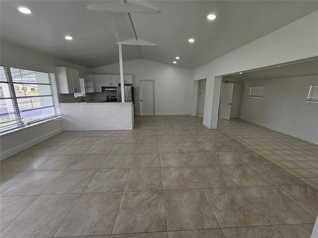 unfurnished living room with light tile patterned floors and lofted ceiling