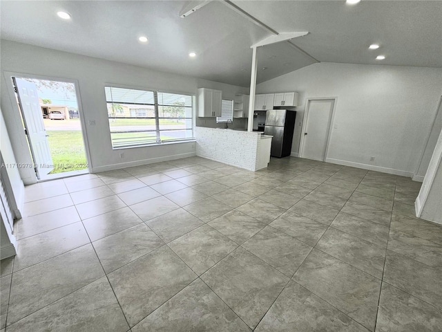 unfurnished living room featuring sink, light tile patterned floors, and vaulted ceiling