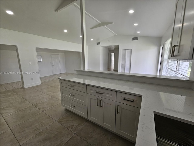 kitchen featuring gray cabinetry, light stone counters, light tile patterned floors, and lofted ceiling