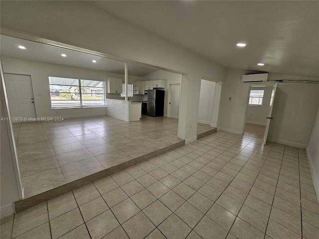 unfurnished living room with vaulted ceiling, light tile patterned floors, sink, and a wall mounted AC