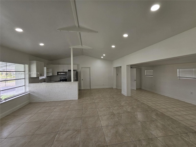 kitchen with stainless steel refrigerator, white cabinetry, vaulted ceiling with beams, kitchen peninsula, and light tile patterned floors