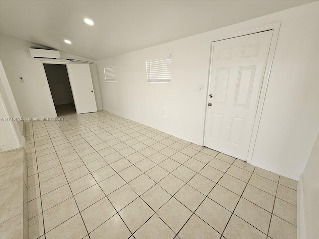 empty room featuring vaulted ceiling, light tile patterned floors, and a wall mounted AC