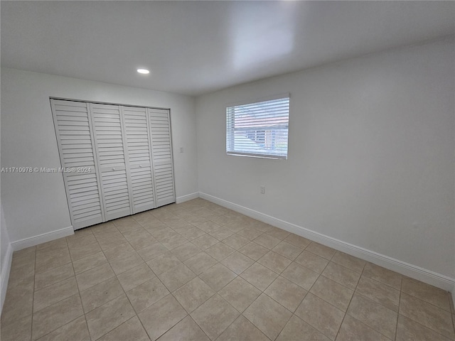 unfurnished bedroom with light tile patterned flooring and a closet