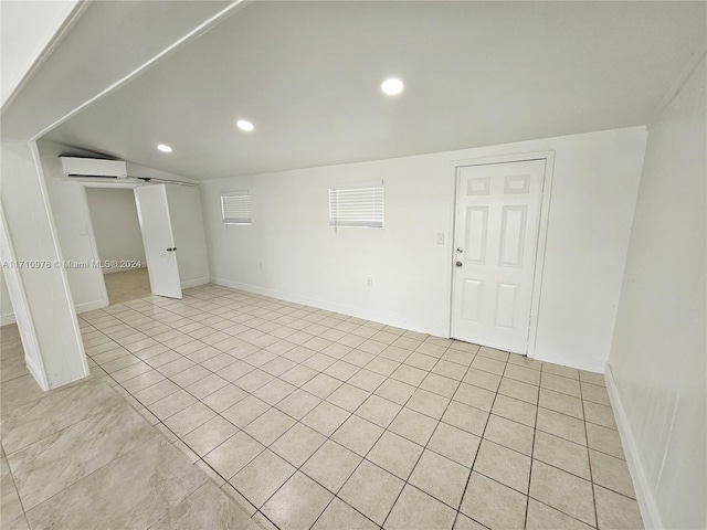 unfurnished room with light tile patterned floors and an AC wall unit