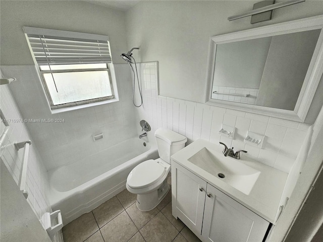 full bathroom with vanity, tile patterned floors, tiled shower / bath combo, toilet, and tile walls