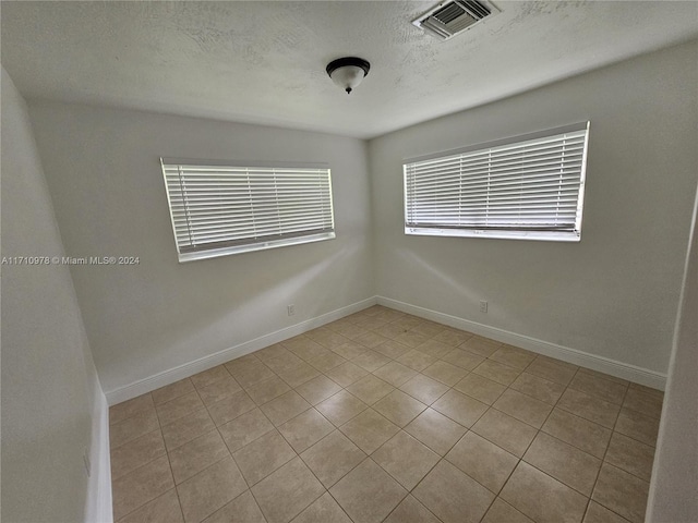 tiled empty room with a textured ceiling