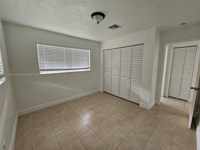 unfurnished bedroom featuring light tile patterned floors and a textured ceiling