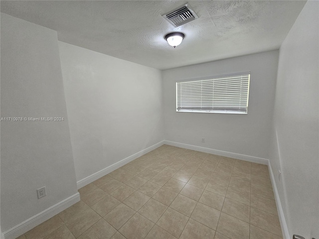 tiled spare room featuring a textured ceiling