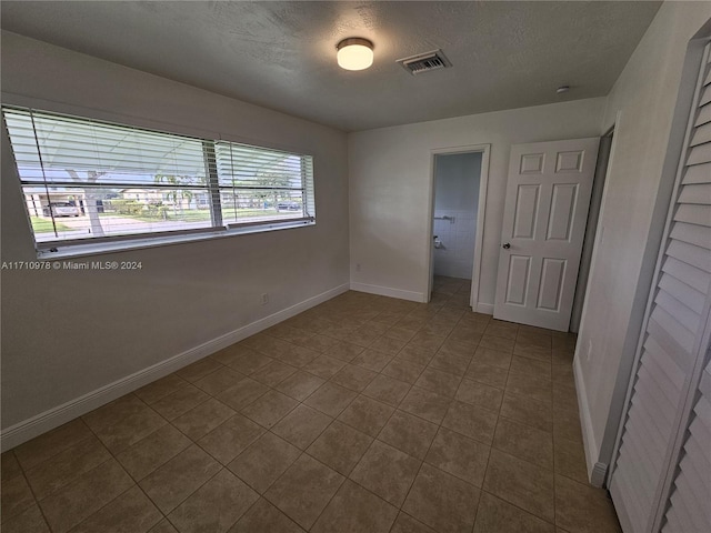 empty room with tile patterned floors and a textured ceiling