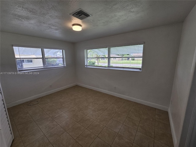 tiled empty room with a textured ceiling