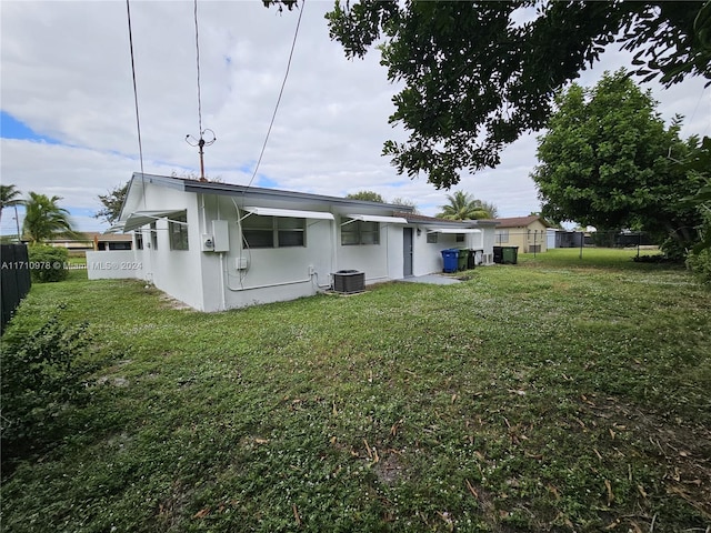 rear view of house with a yard and central AC