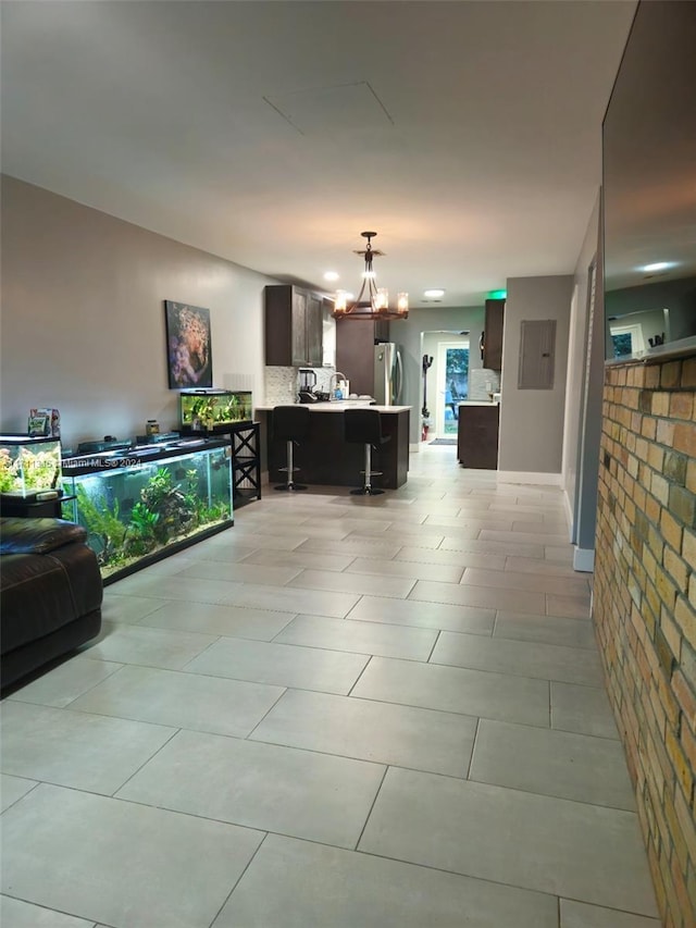 tiled living room featuring electric panel and an inviting chandelier