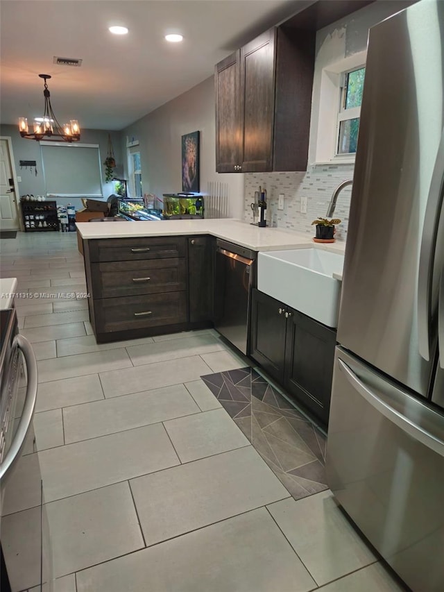 kitchen with dark brown cabinetry, kitchen peninsula, appliances with stainless steel finishes, and a chandelier