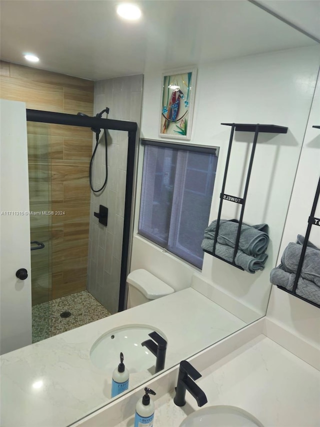 bathroom featuring a shower with door, vanity, and toilet