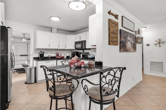 kitchen featuring a kitchen breakfast bar, stainless steel appliances, crown molding, light tile patterned floors, and white cabinets