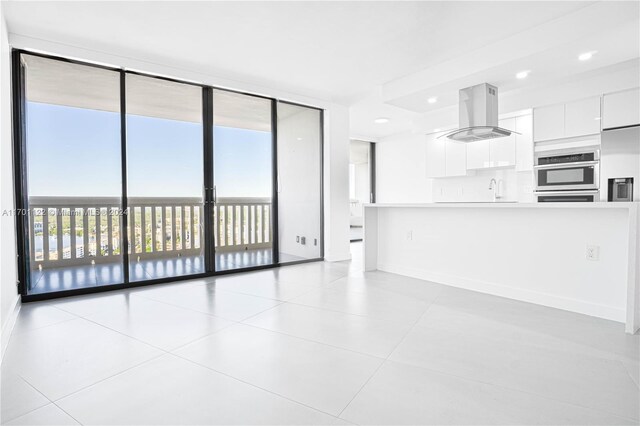 unfurnished living room with sink, a wall of windows, and light tile patterned flooring