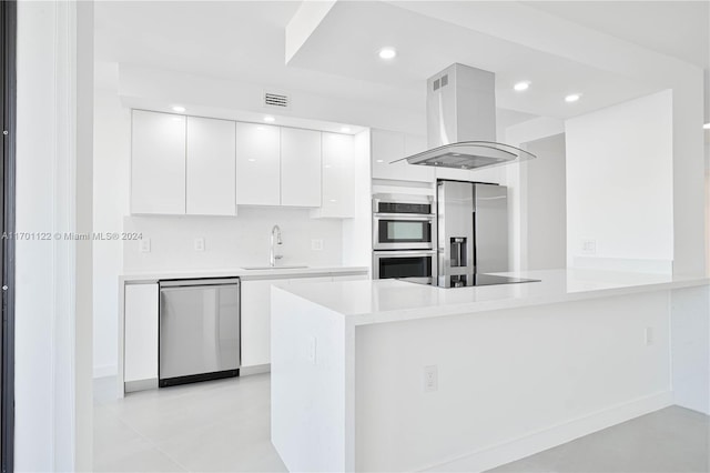 kitchen with kitchen peninsula, island range hood, white cabinetry, and stainless steel appliances