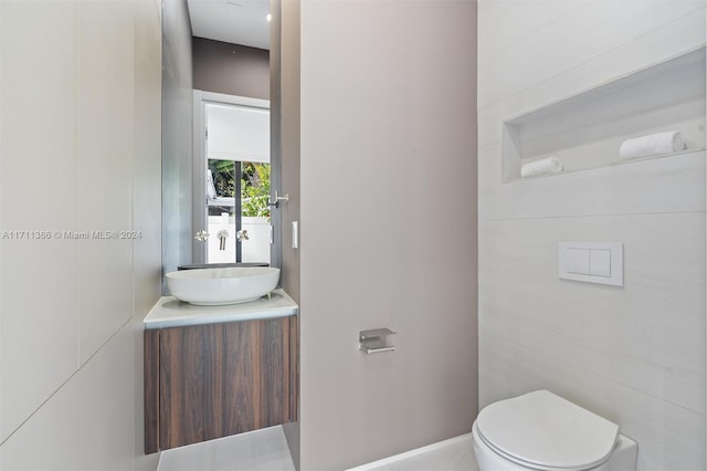 bathroom with vanity, toilet, and tile walls