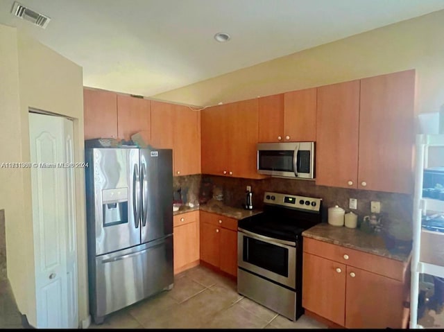 kitchen with light tile patterned floors, backsplash, and stainless steel appliances