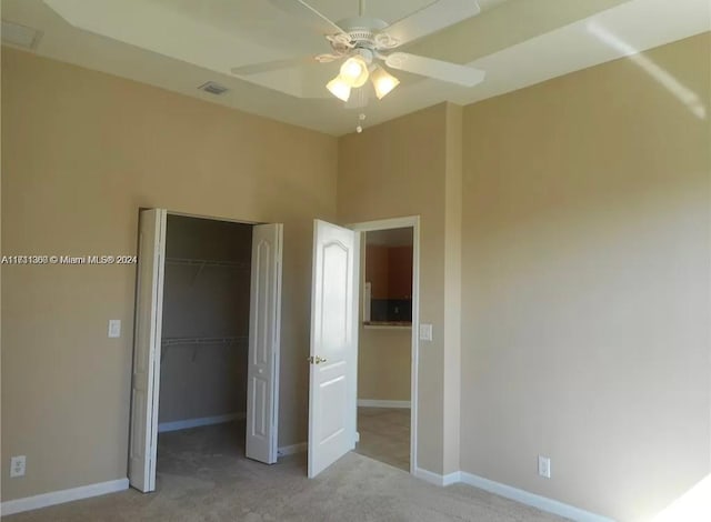 unfurnished bedroom with ceiling fan, light colored carpet, and a closet