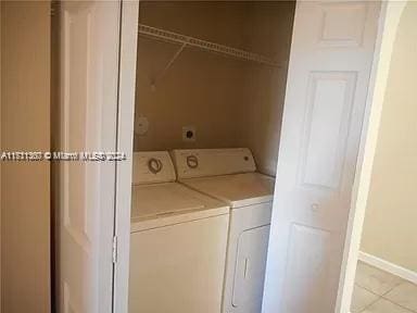 clothes washing area featuring light tile patterned floors and washer and dryer