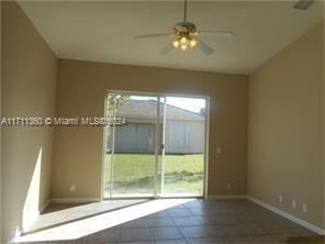 empty room featuring ceiling fan, plenty of natural light, and tile patterned flooring