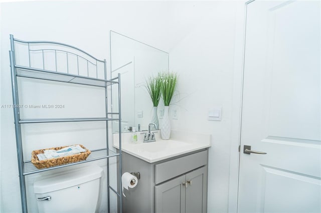 bathroom featuring vanity, toilet, and lofted ceiling