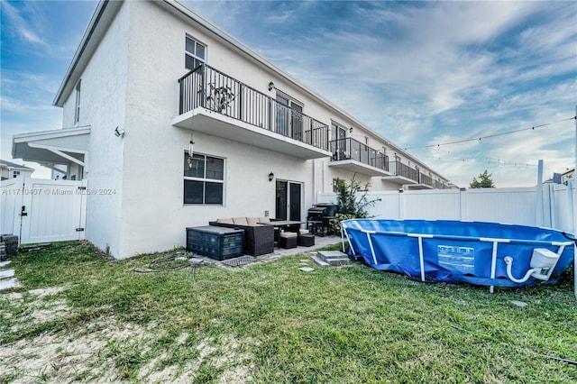 rear view of house featuring a lawn, outdoor lounge area, and a covered pool